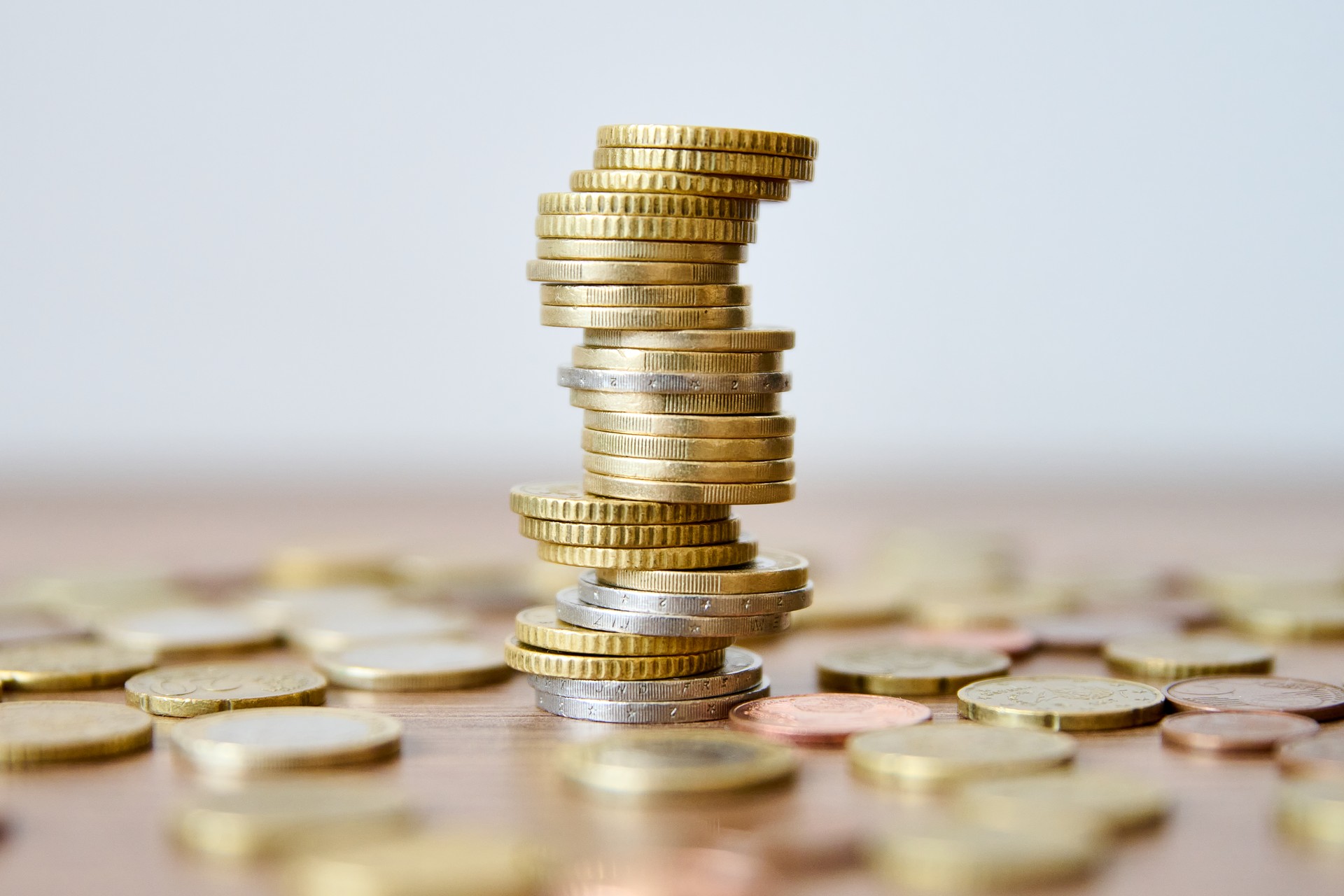 Pile of coins on a wooden table with shallow depth of field