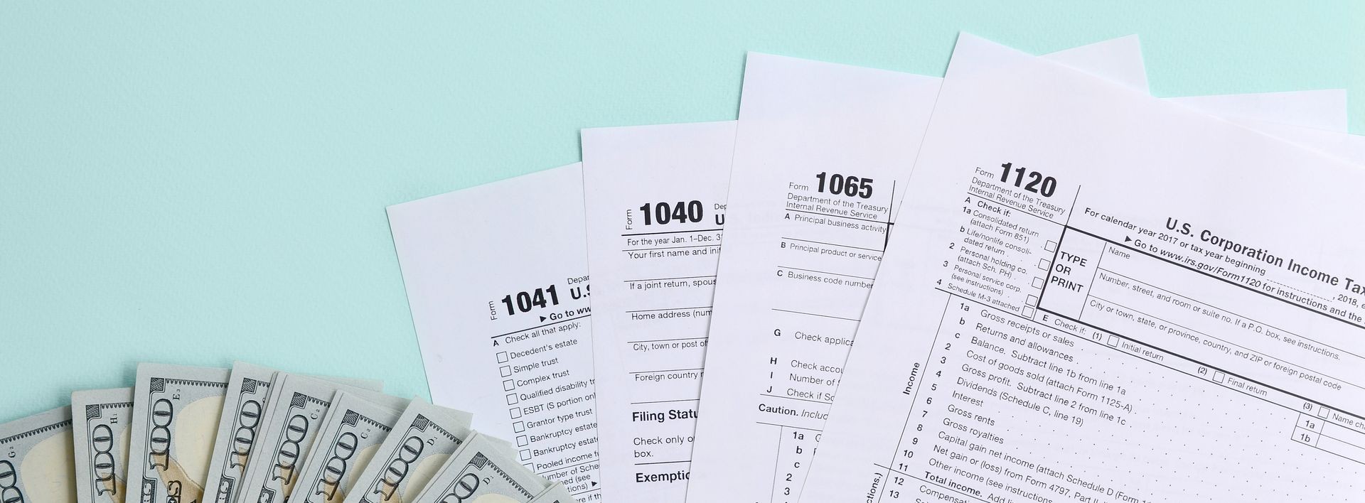 Tax forms lies near hundred dollar bills and blue pen on a light blue background. Income tax return